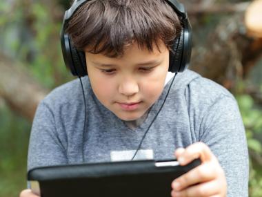 Dreng med høretelefoner på, der kigger på sin iPad 